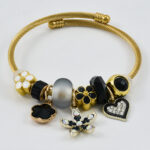 Gouden armband met zwarte en gouden bedels en luxe uitstraling