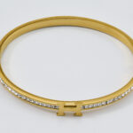 Gouden bangle met een gegraveerde tekst en sprankelende steentjes