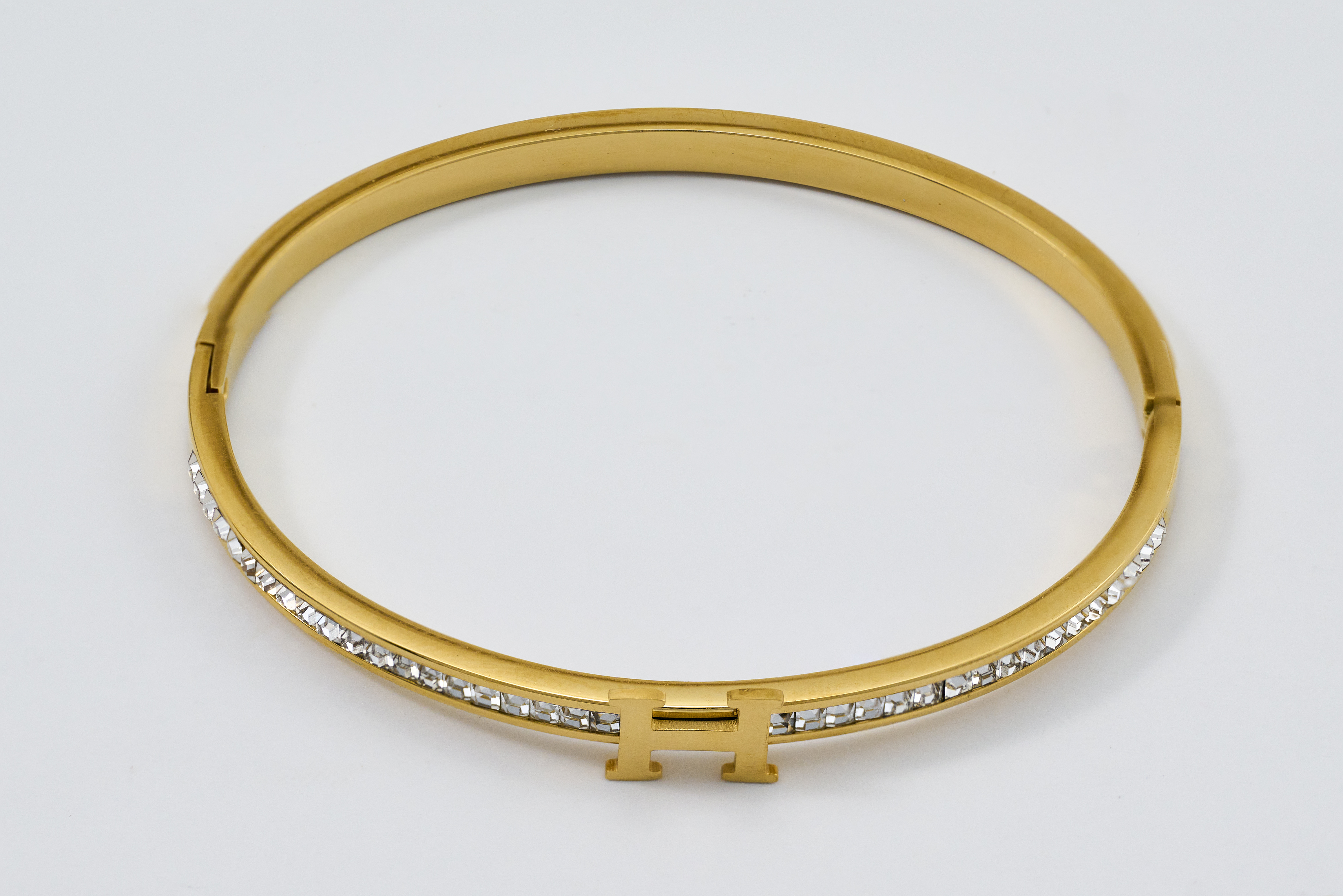 Gouden bangle met een gegraveerde tekst en sprankelende steentjes