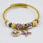 Gouden bangle met kleurrijk gevlochten koord en sluiting